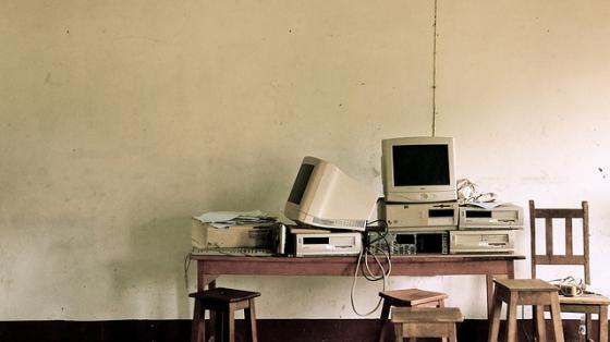 A pile of old computers stacked up on a desk