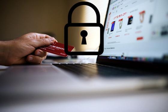 laptop with a hand holding a credit card and a padlock