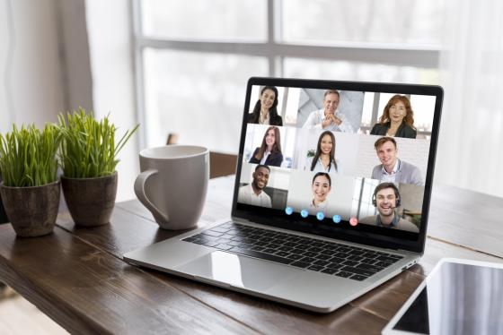Business video call on a laptop with screen showing lots of faces. 