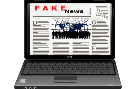 A laptop open showing Fake News as the headline