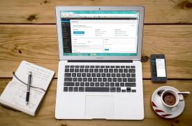 Laptop open with Wordpress showing with a notebook next to it