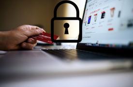 laptop with a hand holding a credit card and a padlock