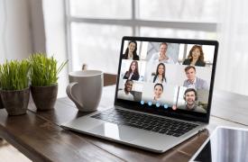 Business video call on a laptop with screen showing lots of faces. 